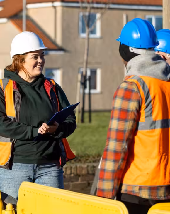 Construction workers and supervisor discussing project plans outdoors.