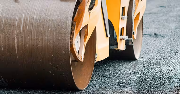 Road roller compacting asphalt on street in Northfield Township.